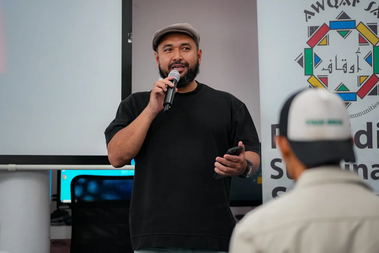 Khaalid speaking into a microphone during a live workshop session