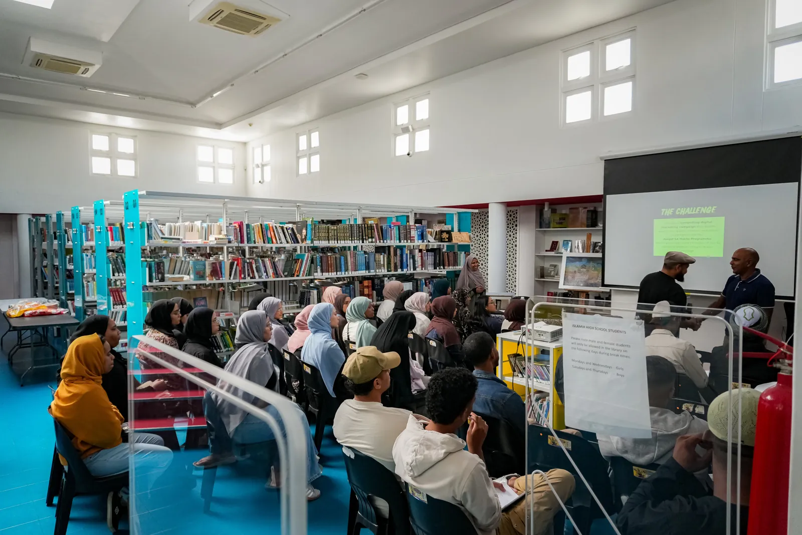 Attendees seated in rows facing a presentation screen in the library